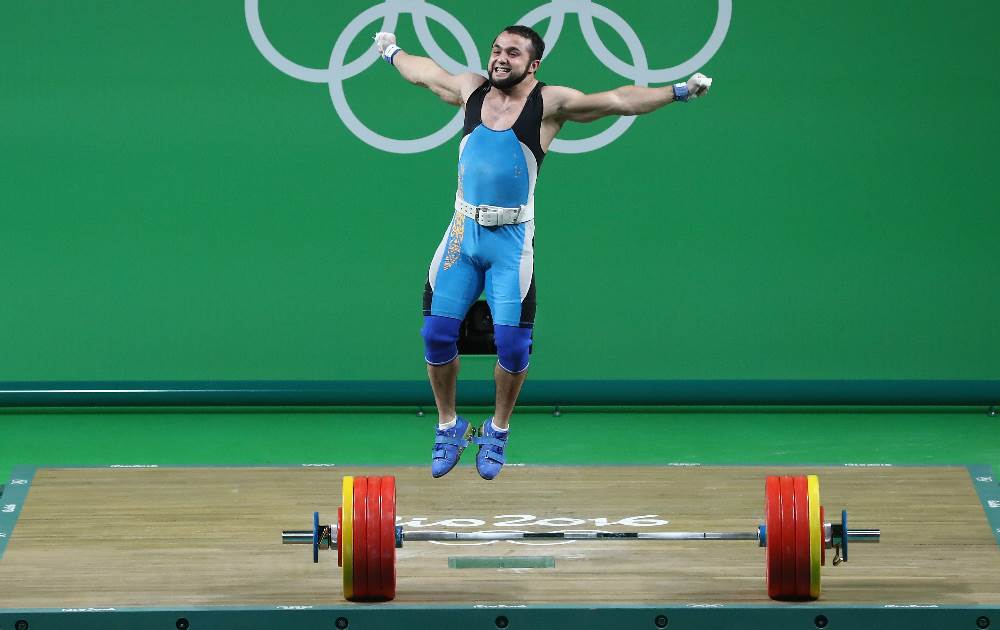 Cazaque Nijat Rahimov salta para comemorar o ouro Olímpico no levantamento de peso. FOTO: Getty Images/Julian Finney